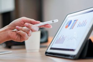 hand using stylus to point to charts on a tablet screens