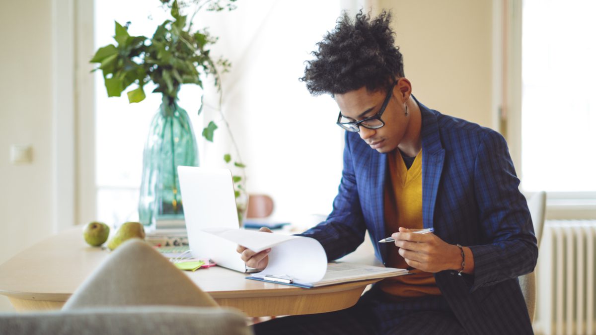 Young professional looking as a clipboard with documents while sitting at a table