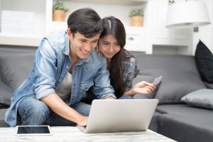 Couple holding credit card while looking at laptop together