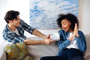 Young man holding out gift to young lady