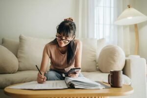 Girl sitting and writing notes while wearing glasses