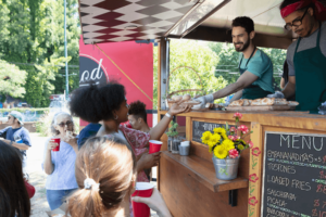 People buying food from food truck outside.