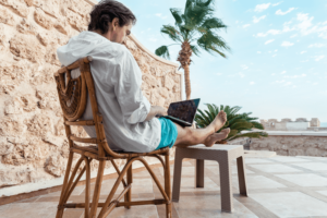 Freelancer with a laptop in his hands works on vacation.