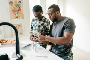 Man standing at counter with son teaching him about money