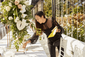 Shot of a young woman decorating a table with place card holders in preparation for a wedding reception.