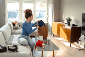 Woman packing emergency supplies in a modern living room.